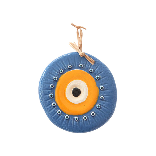 A ceramic wall hanging with a central orange eye motif surrounded by smaller eye motifs on a blue background, with a loop for hanging.
