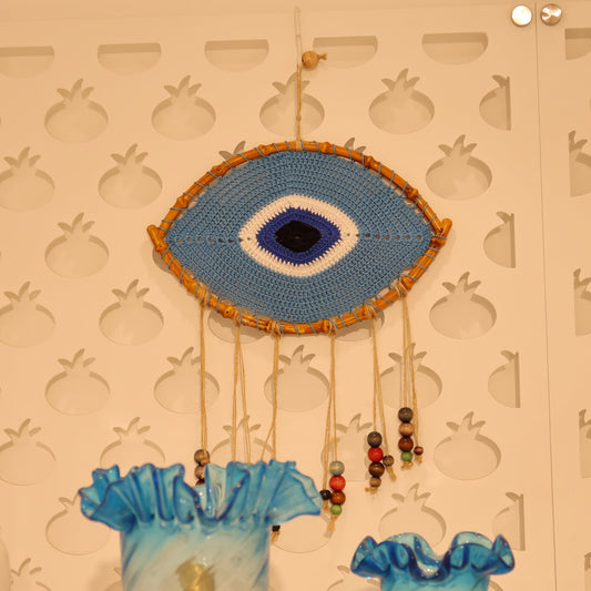 Decorative wall art with a blue eye design on a textured beige background