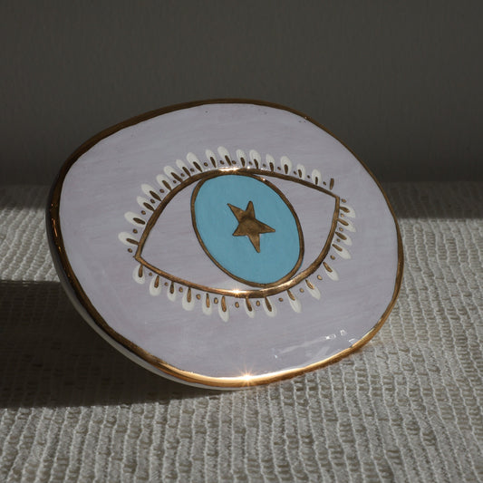 Circular enamel pin with eye design on a textured surface