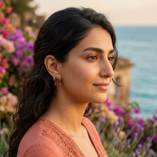 Woman with dark hair and a pink top standing in front of flowers and water.