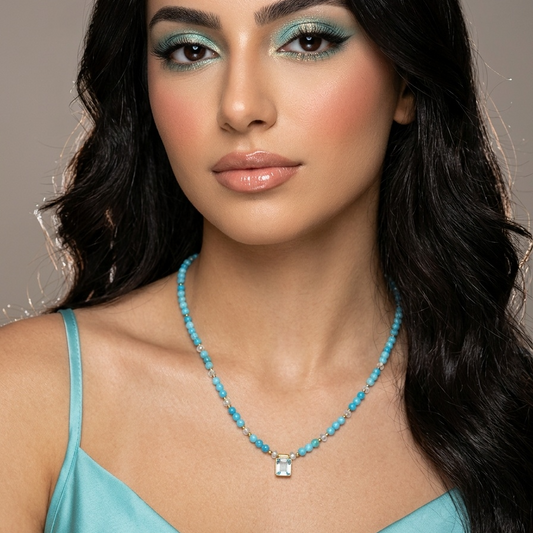Woman wearing a turquoise necklace against a neutral background