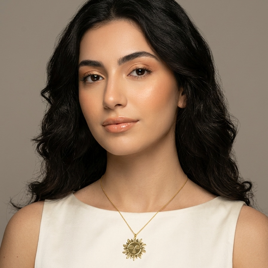 Woman wearing a gold necklace with a sun design against a neutral background