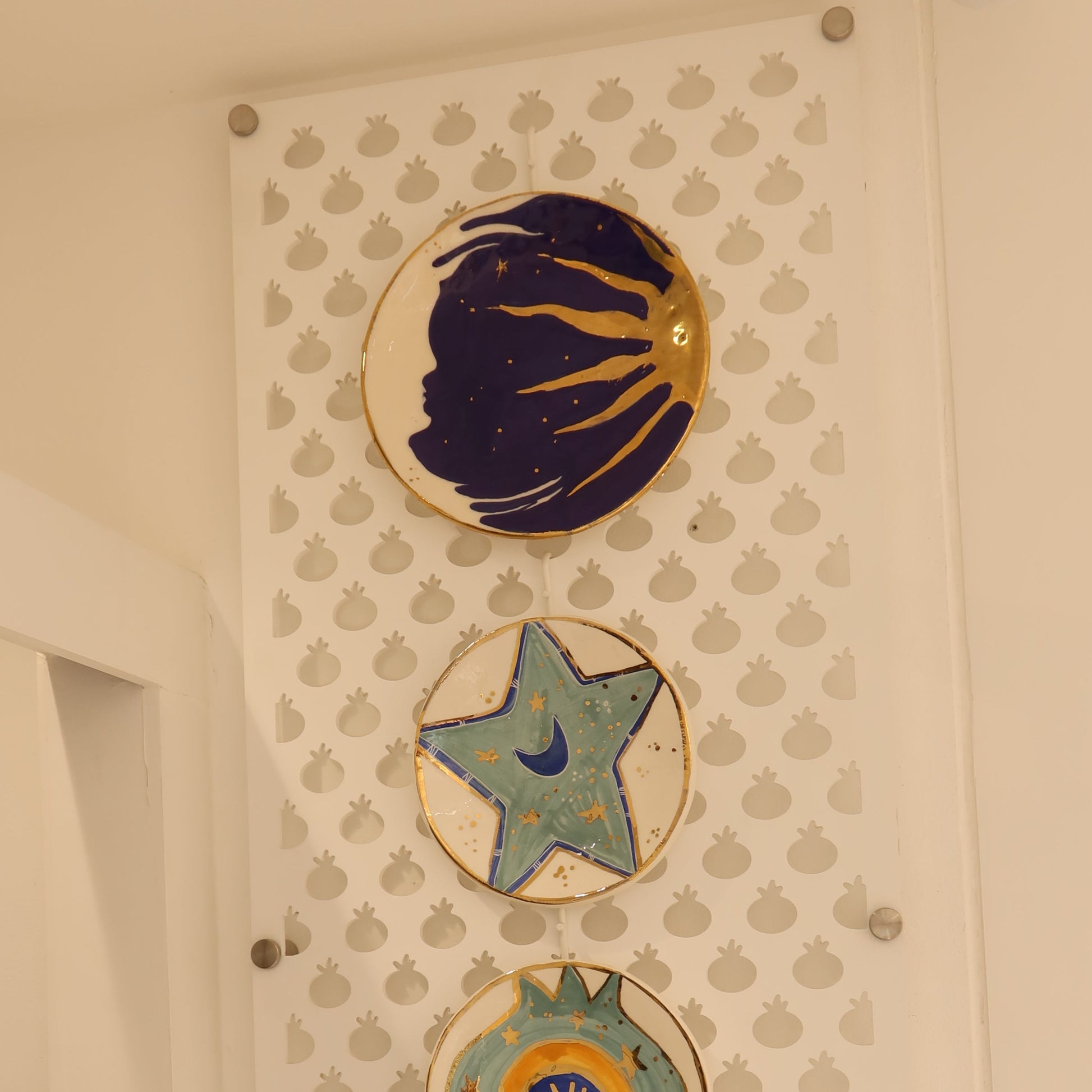 Decorative ceramic plates with star and shell designs on a textured wall.