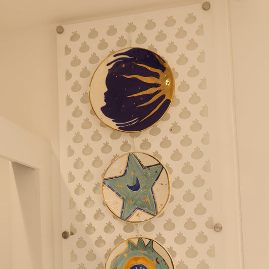 Decorative ceramic plates with star and shell designs on a textured wall.