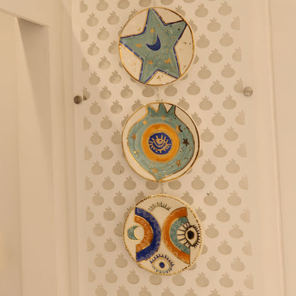Decorative ceramic plates with star and shell designs on a textured wall.