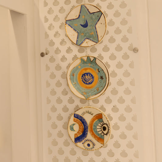 Decorative ceramic plates with star and shell designs on a textured wall.