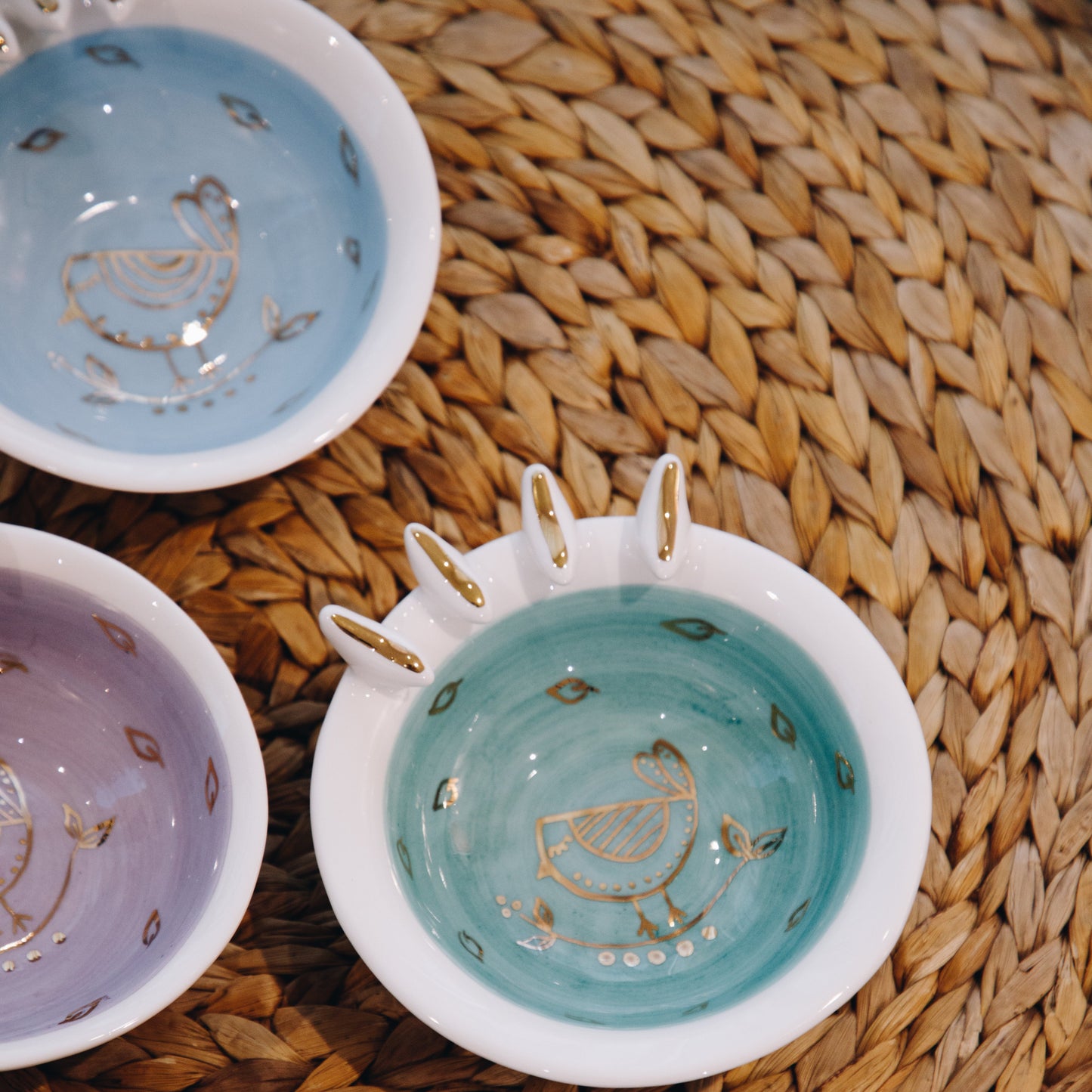 Three ceramic bowls with decorative patterns on a woven mat