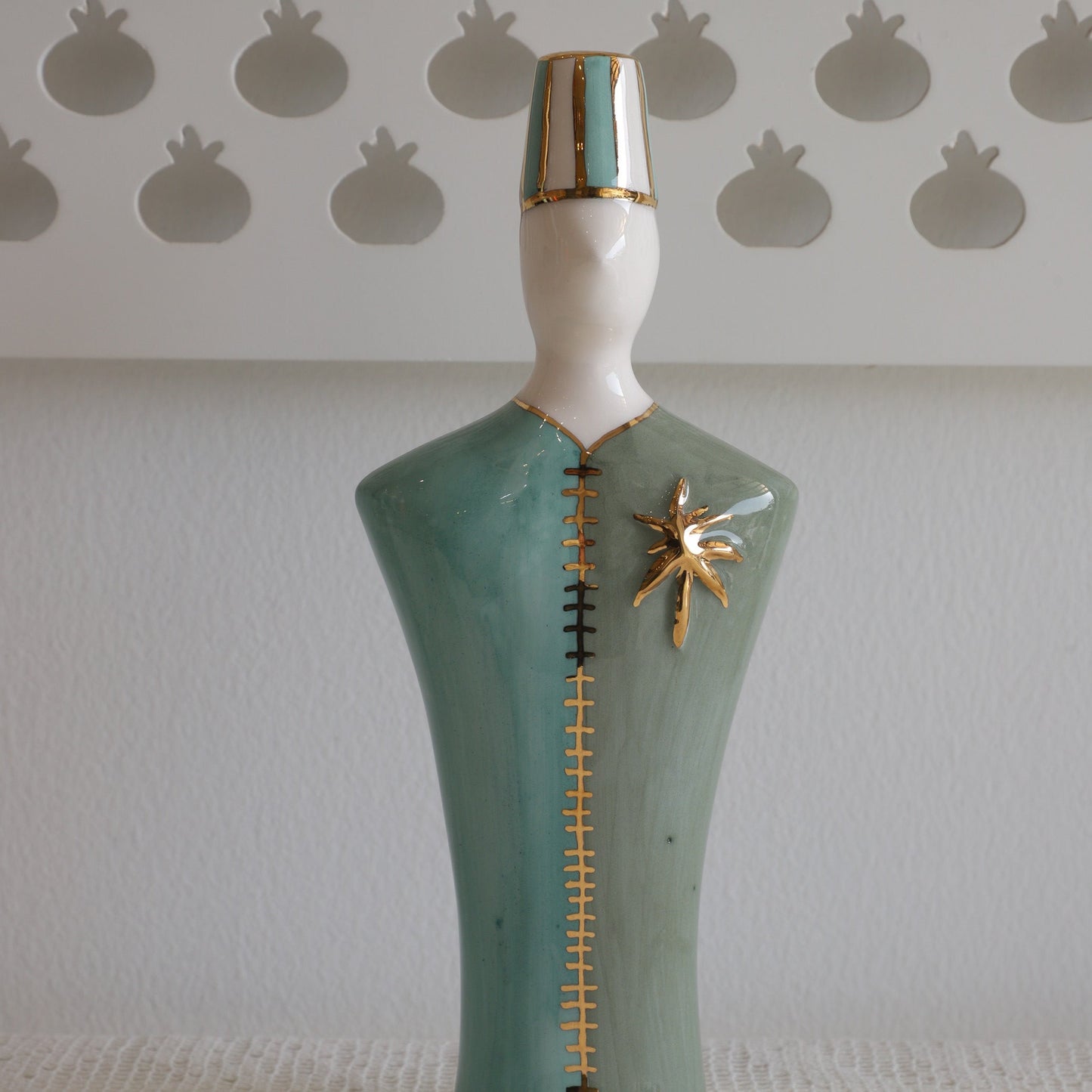Decorative item with a green base, white top, and gold accents on a textured surface.