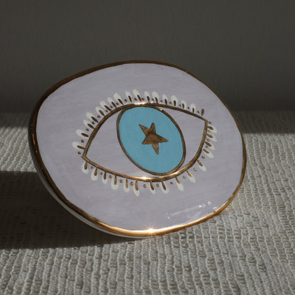 Circular enamel pin with eye design on a textured surface