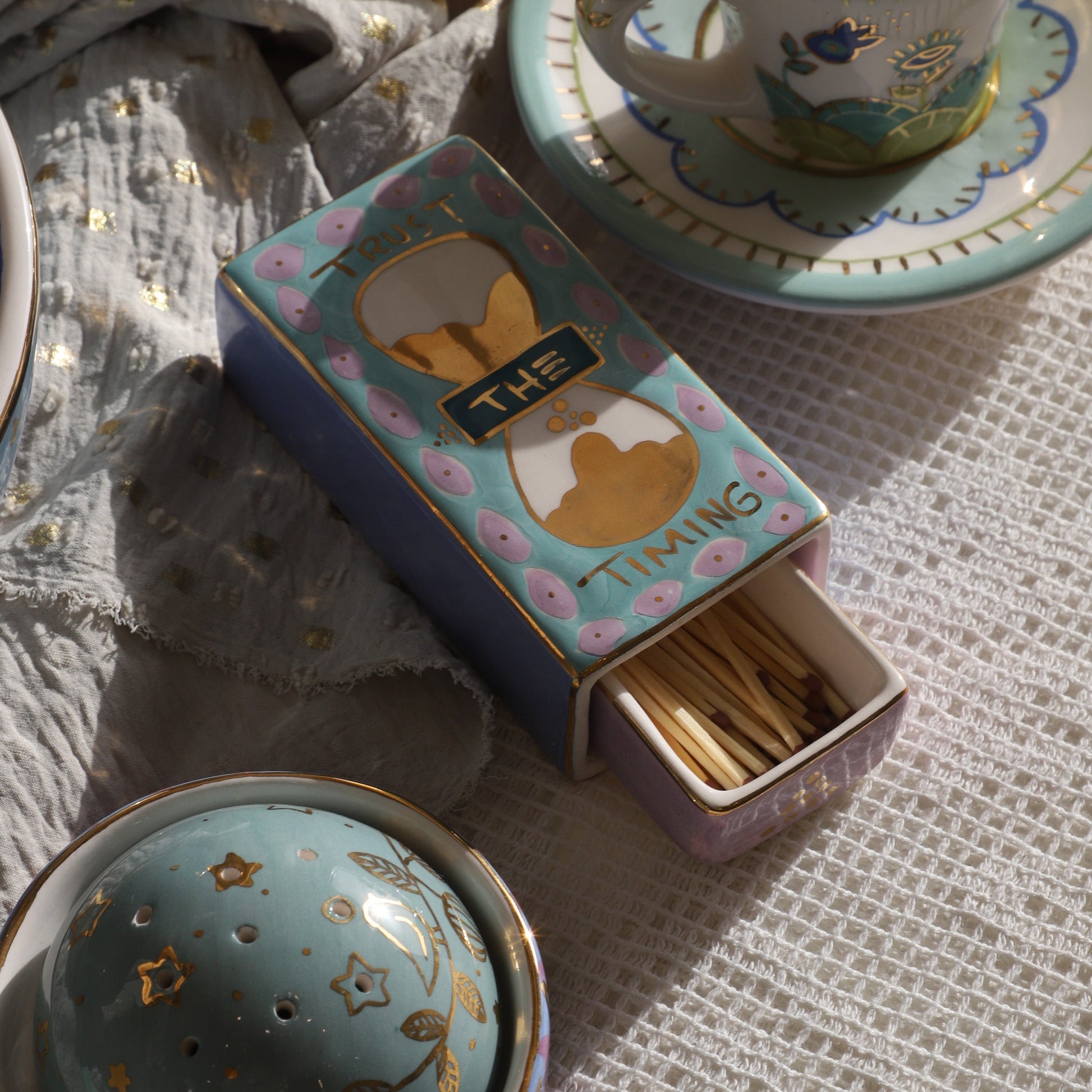 Tea set with a matchbox and decorative elements on a textured surface
