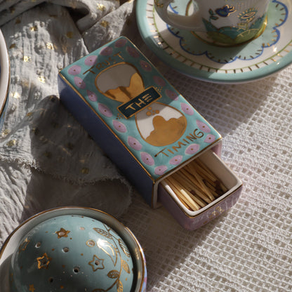 Tea set with a matchbox and decorative elements on a textured surface