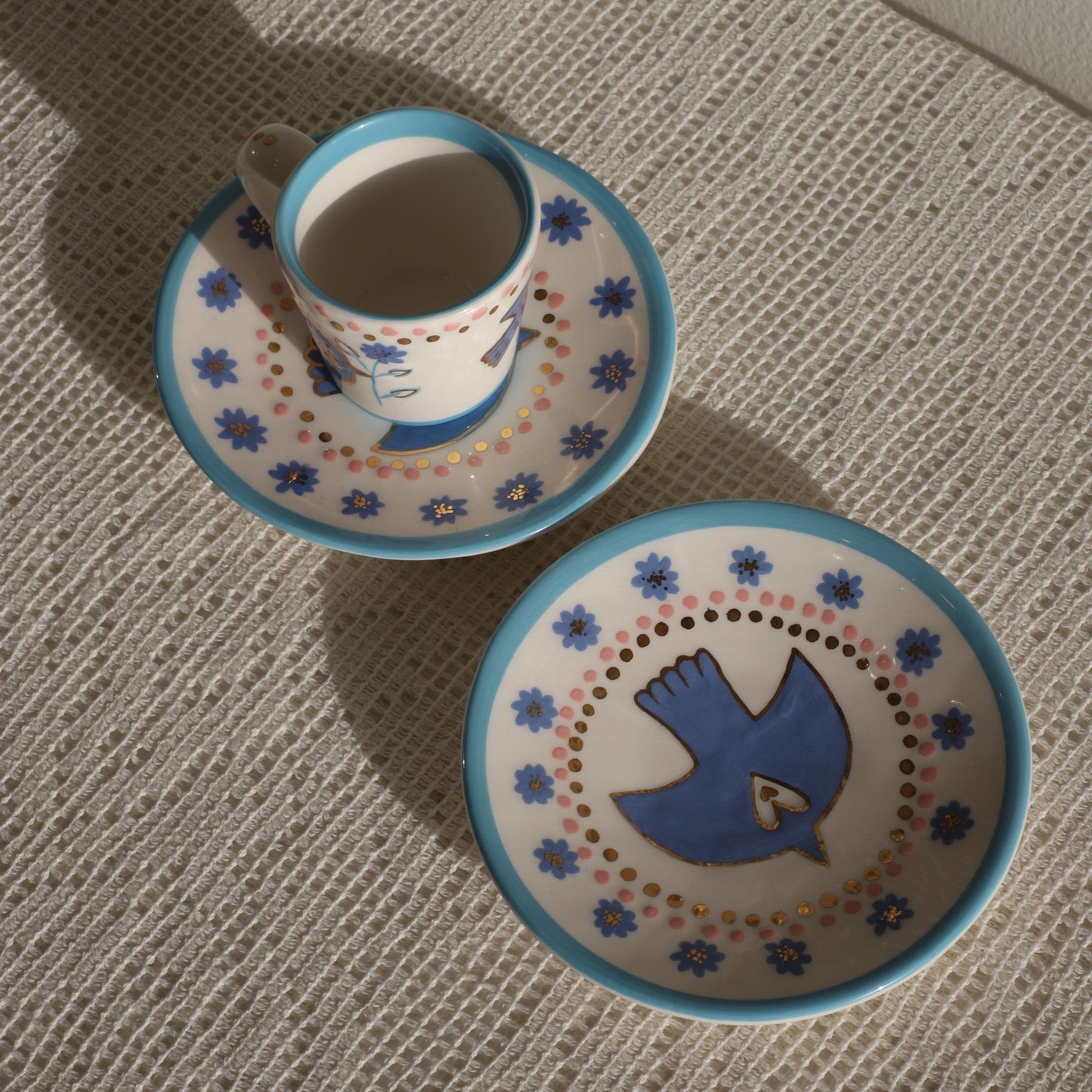 Ceramic bowl and saucer with decorative blue bird design on a textured surface
