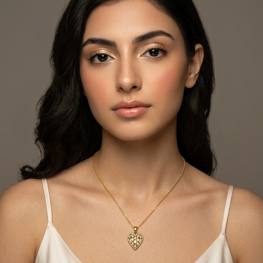 Woman wearing a gold necklace with a heart pendant against a neutral background